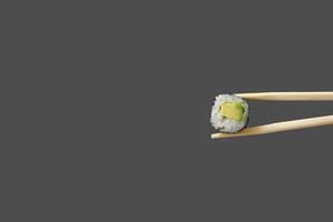 fresh vegetarian maki sushi roll with wooden chopsticks isolated on grey background. copy space photo