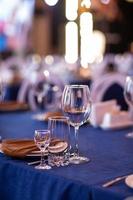 mesa elegante con platos blancos con servilletas sobre mantel azul, vajilla servida en una mesa vacía en un restaurante, vasos vacíos, concepto de vajilla de lujo. enfoque selectivo
