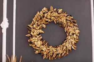 Christmas wreath decoration with golden leaves on gray wall. copy space photo