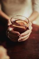 Young bride drinking tea. Wedding bouquet on a wooden table in a restaurant. Cropped image of bride which holding a cup of tea with lamon photo