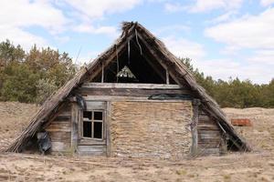 traditional old rustic building with a roof covered with straw on early spring day, Ukraine. tourist place photo