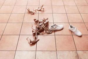 Female casual and luxury shoes. Woman's shoes on floor. Footwear laying on tile. So many different shoes. photo