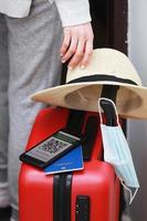 nuevo concepto normal. mujer lista para viajar con un teléfono inteligente con un pasaporte de salud digital inmune. mujer con máscara protectora, sombrero de paja y pasaporte viaja en avión durante una pandemia. foto