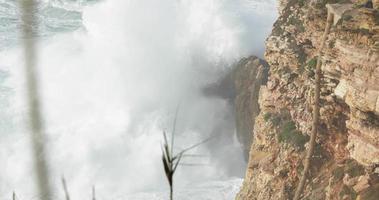 die schönen wellen, die am felsigen bergufer von nazare, portugal, krachen und spritzen - zeitlupe video