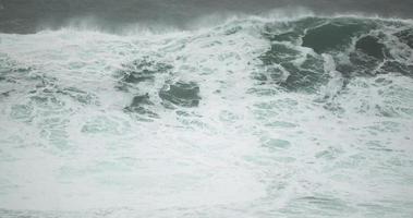 grandes olas espumosas rompiendo junto al mar en nazare, portugal en cámara lenta - toma de primer plano video