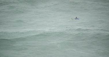 A lifeguard on a jetski watching surfers on the waves of Nazare - slow motion video