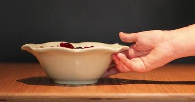 Hand Serving A Fruit Cereal Bowl On Wooden Table With Black Background - Closeup Shot video