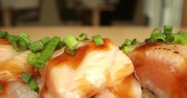 rollos de sushi de salmón adornados con cebollino de cebolla fresca - macro, toma panorámica lenta video