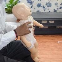 hombre realizando RCP en un maniquí de muñeca de entrenamiento para bebés con compresión con una mano. formación en primeros auxilios - reanimación cardiopulmonar. curso de primeros auxilios en maniquí de cpr, concepto de capacitación en primeros auxilios de cpr foto