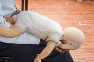 hombre realizando RCP en un maniquí de muñeca de entrenamiento para bebés con compresión con una mano. formación en primeros auxilios - reanimación cardiopulmonar. curso de primeros auxilios en maniquí de cpr, concepto de capacitación en primeros auxilios de cpr foto