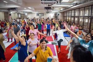 Delhi, India, June 19 2022 -Group Yoga Aerobics session for people of different age groups in Balaji Temple, Vivek Vihar, International Yoga Day, Big group of adults attending aerobics class in temple photo
