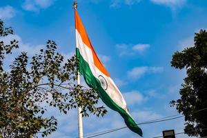 India flag flying high at Connaught Place with pride in blue sky, India flag fluttering, Indian Flag on Independence Day and Republic Day of India, tilt up shot, Waving Indian flag, Har Ghar Tiranga photo