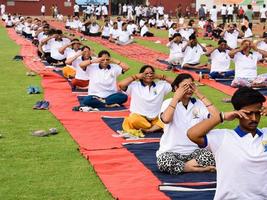 New Delhi, India, June 21 2022 - Group Yoga exercise session for people at Yamuna Sports Complex in Delhi on International Yoga Day, Big group of adults attending yoga class in cricket stadium photo