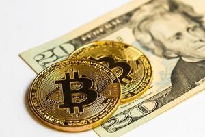 Gold bitcoin on a white background next to us paper money with a face value of dollars photo