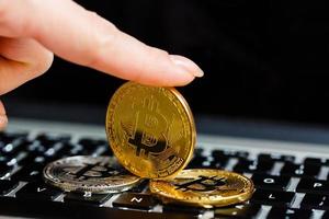 Golden bitcoin in fingers with the laptop keyboard background crypto currency concept photo