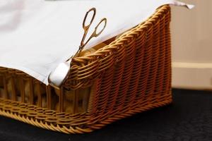 Blurred buffet breakfast on a table. Bread in a wicker basket. Detail of the tongs for take the bread photo