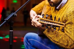 manos de un músico con un traje folclórico tocando en domra tremolo. manos del músico en movimiento. enfoque selectivo. foto