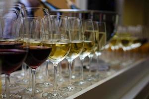 filas de copas de vino con vino tinto y blanco en una mesa de buffet foto