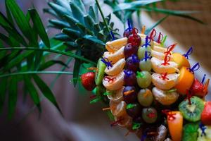 berries and fruit on skewers in pineapple on a buffet table photo