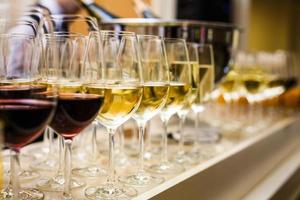 filas de copas de vino con vino tinto y blanco en una mesa de buffet foto