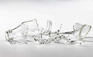 A glass bottle broken into many fragments on a gray background. photo