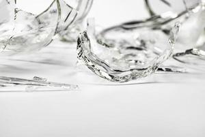 A glass bottle broken into many fragments on a light gray background. photo