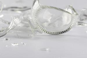 A glass bottle broken into many fragments on a gray background. photo