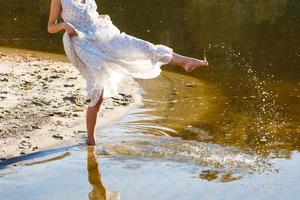 Young woman in white dress walking alone on the beach photo