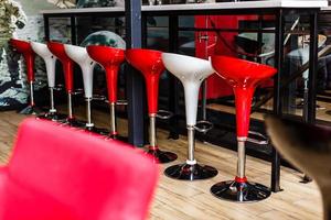 Left side of a row of red and pink square bar stools photo