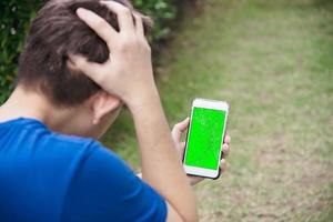 Man seriously looking at mobile phone with broken cracked screen display need to be fixed, mobile repair shop concept photo