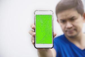 el hombre que mira seriamente el teléfono móvil con la pantalla rota rota necesita ser reparado, el concepto de taller de reparación móvil foto