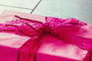 gift with pink ribbon,heart and band on wooden background photo