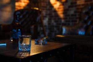 vasos de whisky con cigarro humeante y cubitos de hielo en la mesa de madera