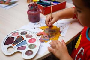 A young beautiful girl is painting autumn maple leaf photo