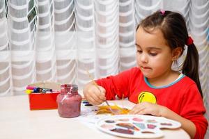 Little girl painting on autumn yellow leaves with gouache kids arts children creativity autumn art photo