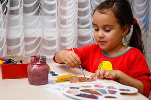 niña pintando sobre hojas amarillas de otoño con gouache artes infantiles creatividad infantil arte otoñal foto