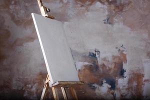 lienzo artístico vacío blanco sobre un caballete para dibujar imágenes de un artista sobre un fondo gris foto
