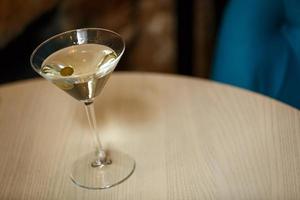 glass with martini , focus on a olives photo