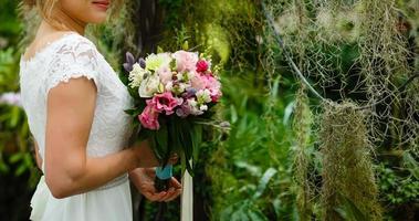 stylish wedding bride smiling, holding bouquet. modern bride hugging groom, lips and earrings close up. photo