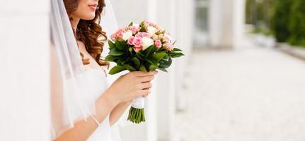 Bridal bouquet beautiful of pink wedding flowers in hands of the bride close up interior studio photo