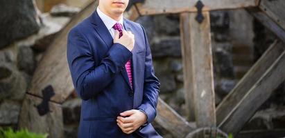 Groom in a suit holding buttonhole photo