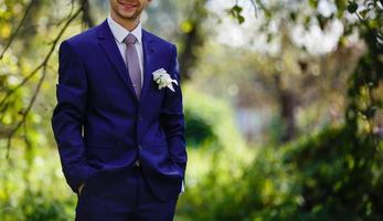 Groom in a suit holding buttonhole photo