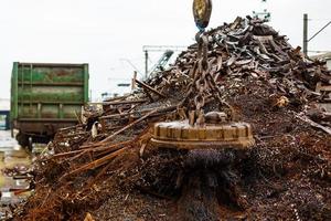 Magnetic crane loading scrap metals at junkyard photo