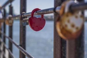 una cerradura de puerta en forma de corazón, símbolo de amor y fidelidad con un lago al fondo, cuelga de la valla del puente. el castillo en forma de corazón simboliza la lealtad y el amor foto