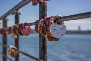 A heart-shaped door lock, a symbol of love and fidelity with a lake in the background, hangs on the fence of the bridge. The heart-shaped castle symbolizes loyalty and love photo