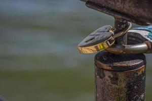 A heart-shaped door lock, a symbol of love and fidelity with a lake in the background, hangs on the fence of the bridge. The heart-shaped castle symbolizes loyalty and love photo