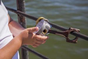 Children and a man walk across the bridge and look at the river. Various interesting things are attached to the railing. A hot summer day photo