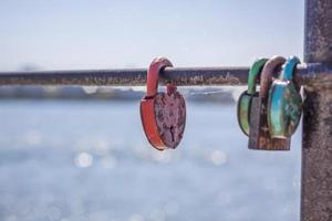 una cerradura de puerta en forma de corazón, símbolo de amor y fidelidad con un lago al fondo, cuelga de la valla del puente. el castillo en forma de corazón simboliza la lealtad y el amor foto