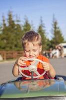 un niño conduciendo un coche para niños. emociones alegres. niños, retrato. foto