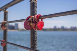 A heart-shaped door lock, a symbol of love and fidelity with a lake in the background, hangs on the fence of the bridge. The heart-shaped castle symbolizes loyalty and love photo